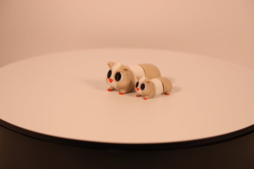 Large and small tan and white articulated 3D‑printed guinea pig desk pets, fidget toys.